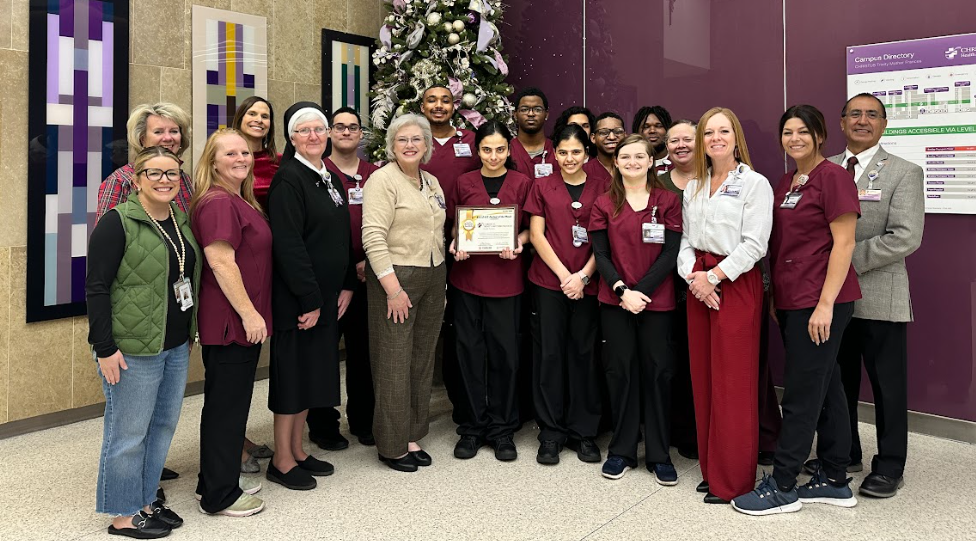 men and women standing in front of a Christmas tree