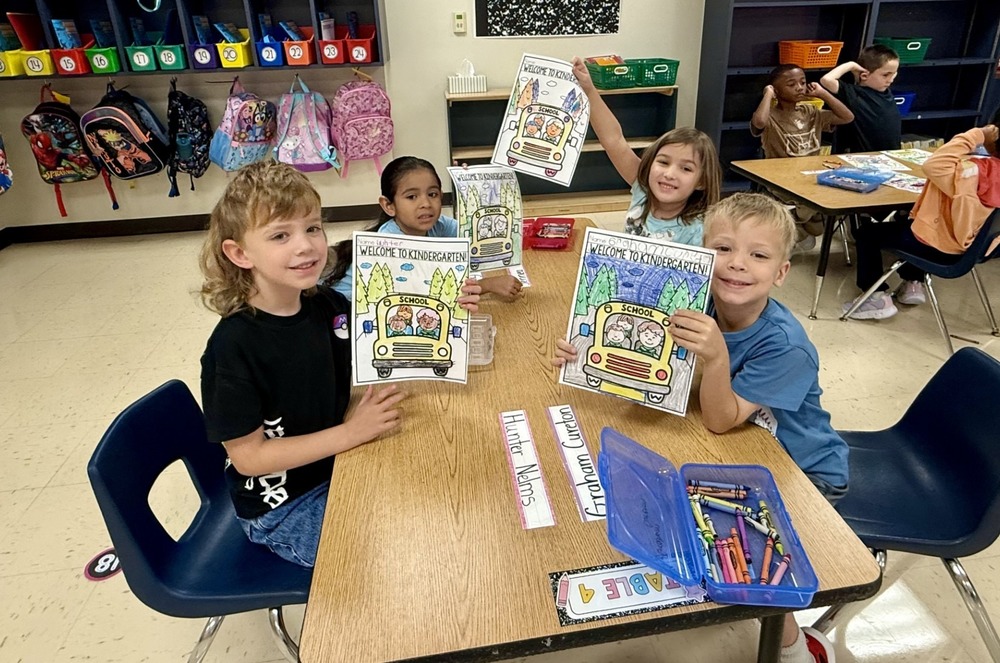kindergarten students showing assignment at table