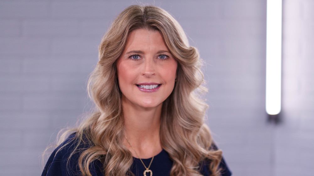 woman with long, blonde, wavy hair wearing navy shirt