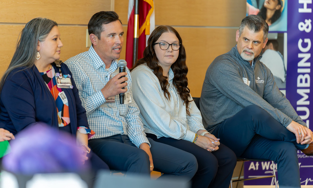 men and women sitting next to each other. one man talking with microphone