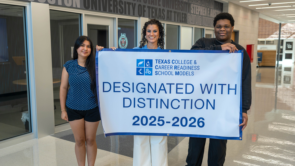 teen girl, teen boy, and woman holding banner in school hallway. The banner reads, "Texas College & Career Readiness School Models. Designated with Distinction, 2025-2026."