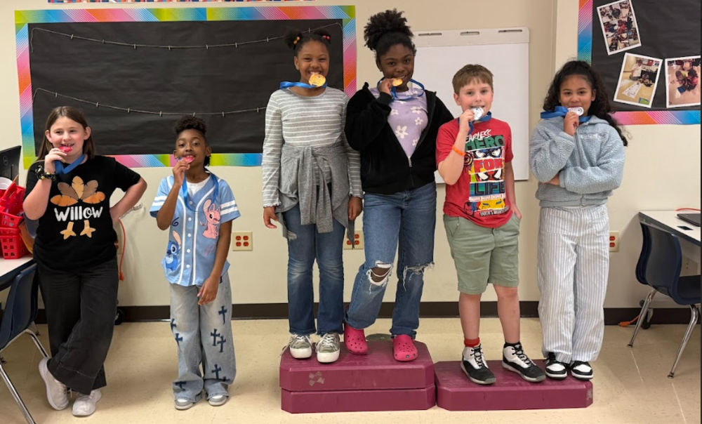 students standing on podium with olympics medals