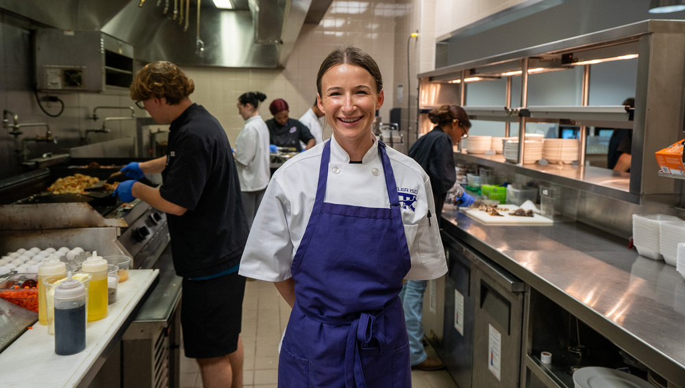 woman standing in kitchen with high school students working behind her