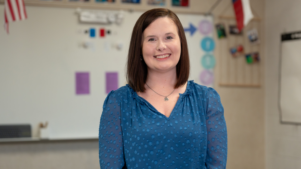 woman with shoulder length brown hair standing in her classroom