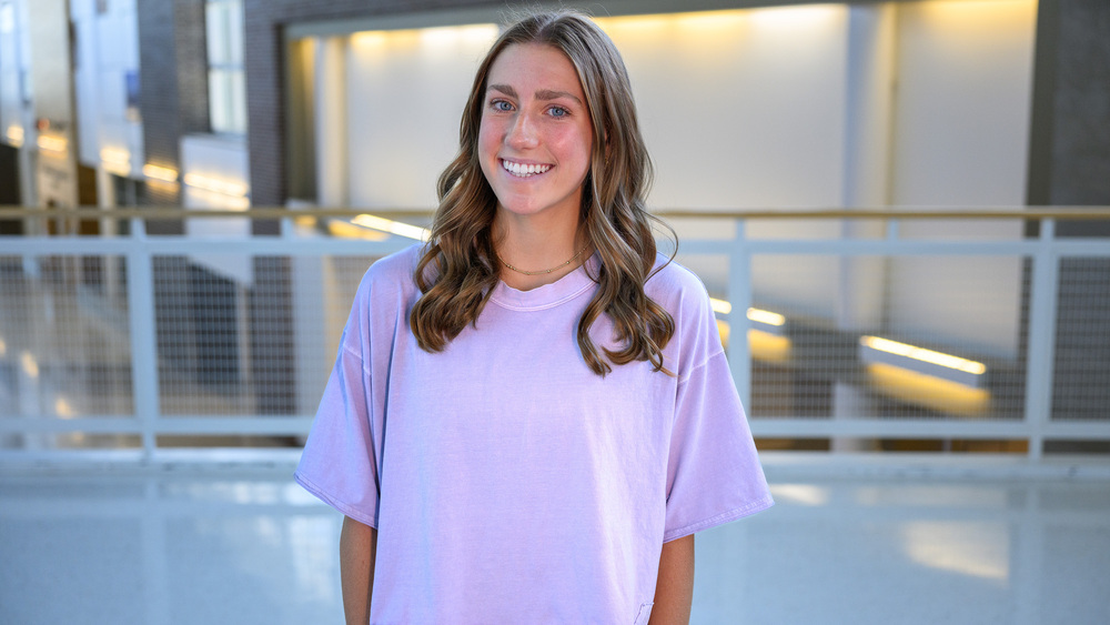 teen girl with long brown hair standing in school hallway