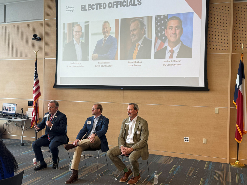 men sitting in chairs talking to crowd