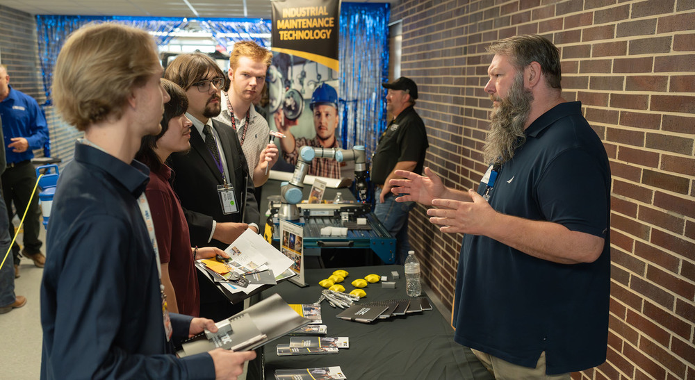 teen boys talking to man with a table between them