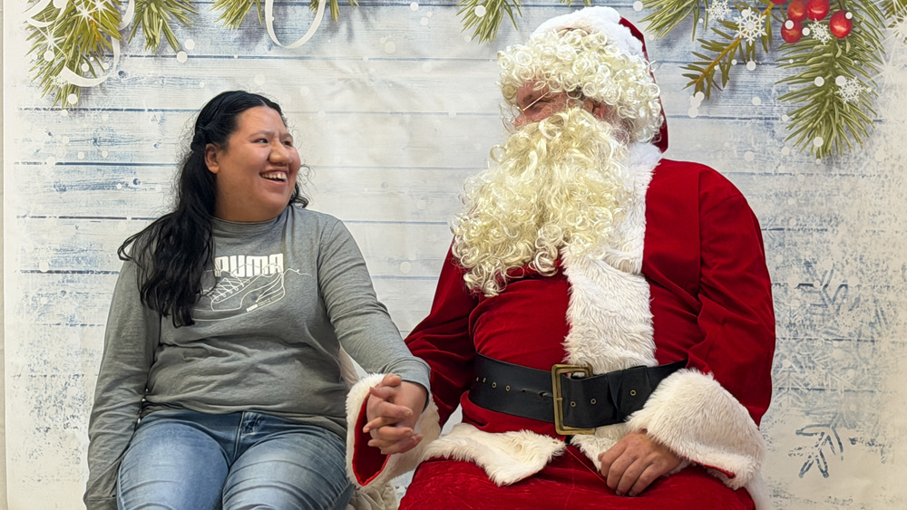 teen girl holding hands and smiling as she looks at Santa