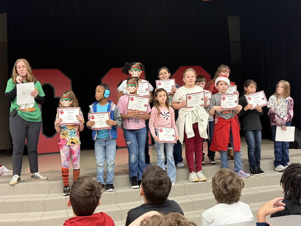 students standing on stage with certificates with principal 