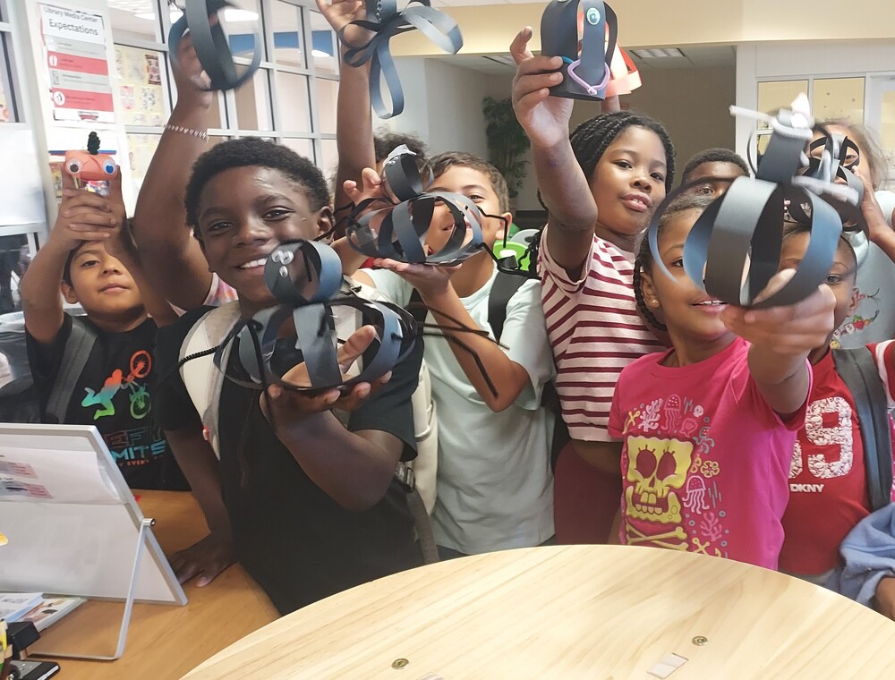 Kids holding up makerspace creatures made of paper