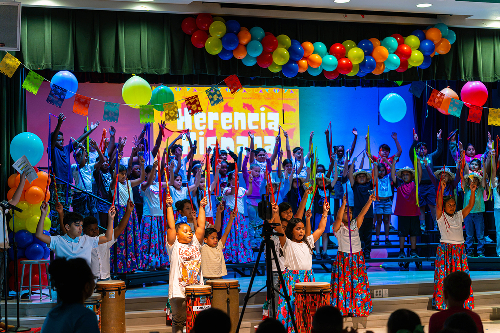 elementary age students in bright colored clothing dancing on stage