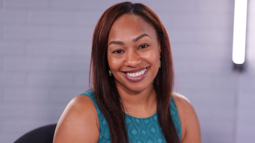 African American woman with straight brown hair wearing a green tank top