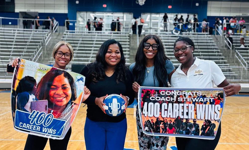 four women standing in middle of gym court holding signs that say, "400 career wins"