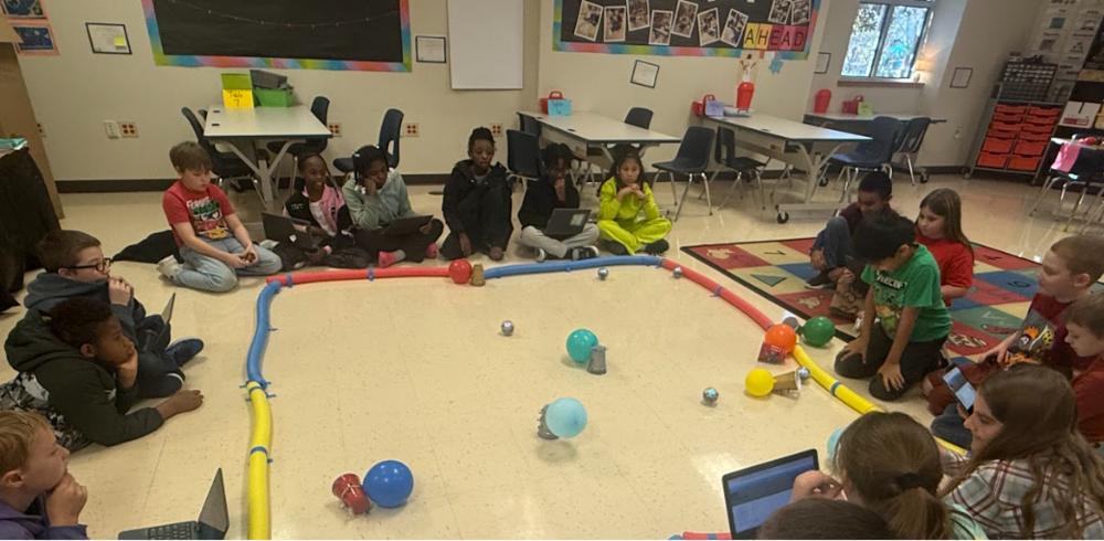 students sitting aorund pool nodle arena with battle bots and balloons