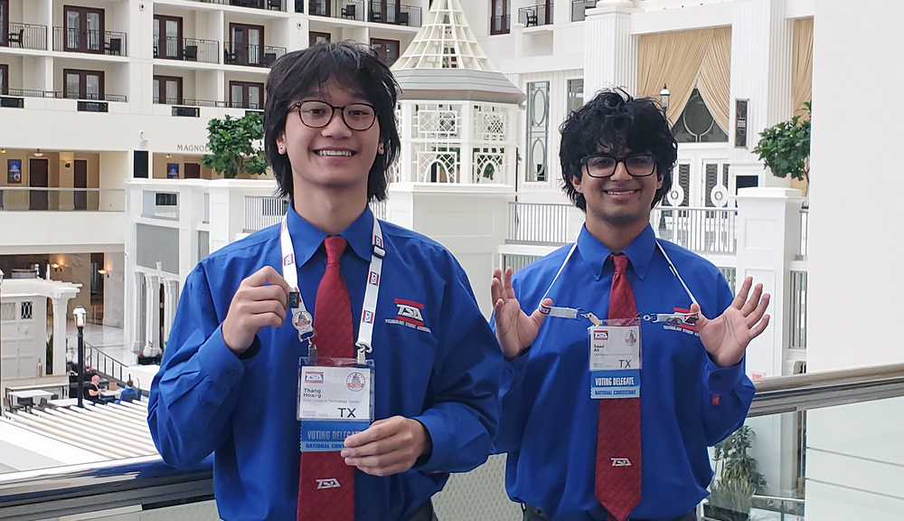 two teen boys with dark hair wearing blue long sleeve button down shirts and red ties