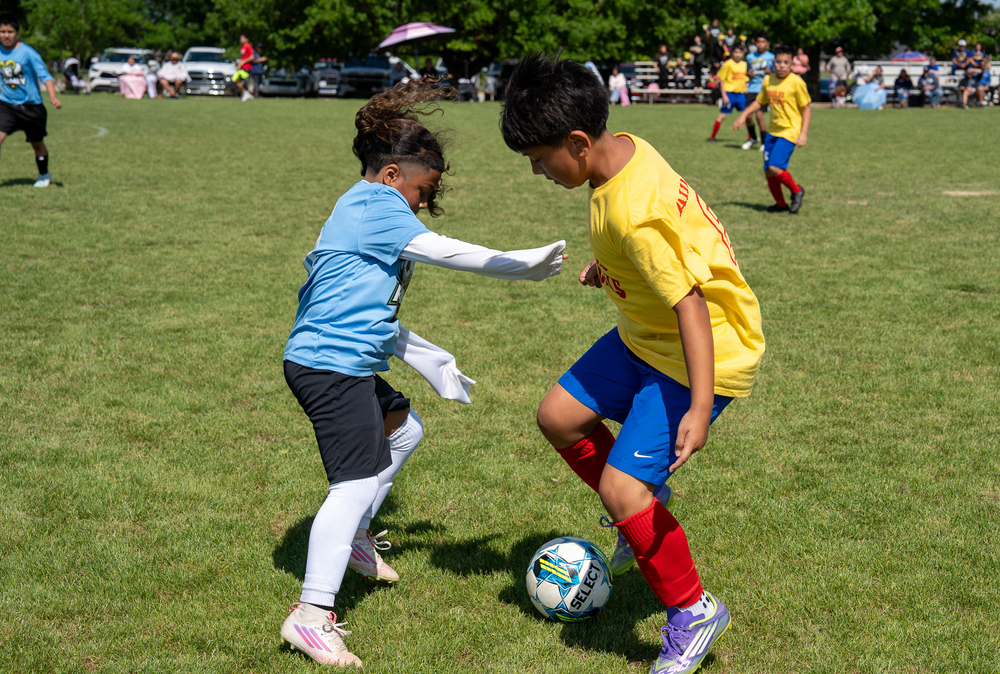 young boy and girl playing soccer on field