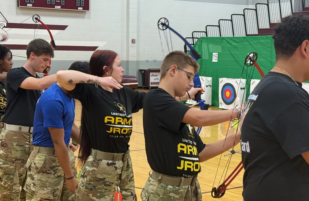teen boys and girls with bows and arrows in archery class