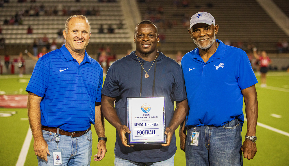 three men standing next to each on football field