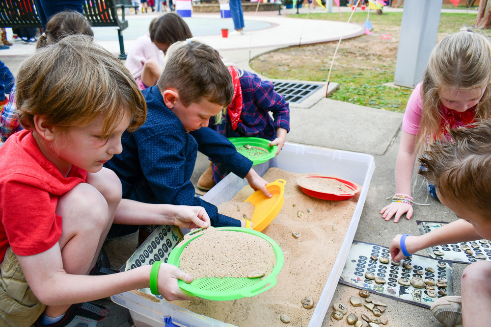 elementary students sifting sand in a box