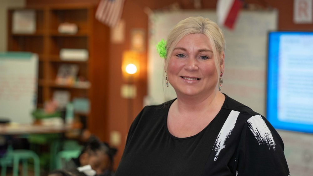 woman with blonde hair wearing black top in classroom