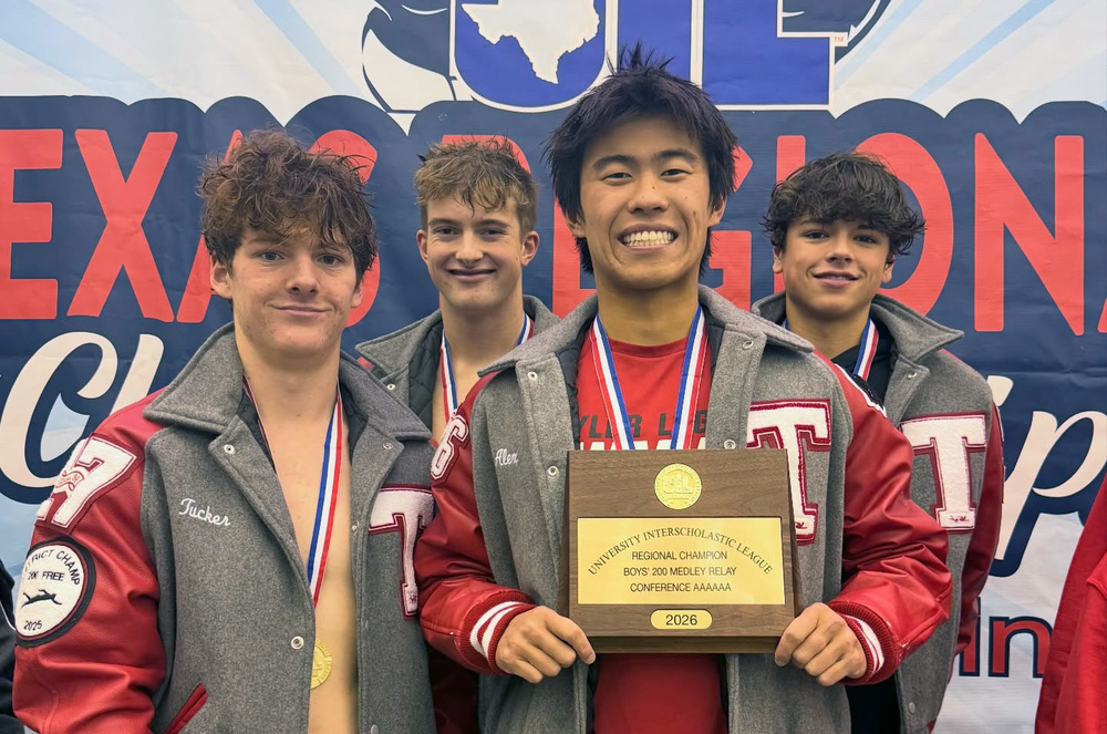 four teen boys wearing letter jackets and medals, one holding a plaque