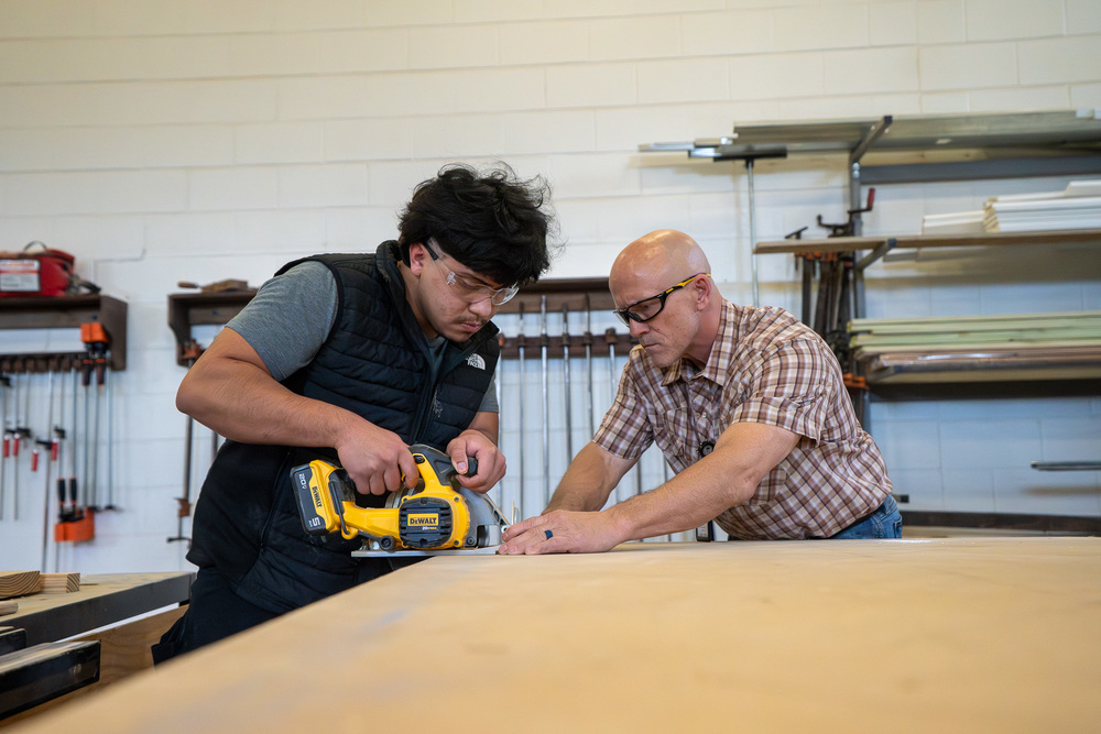 teen boy and man working with saw and wood