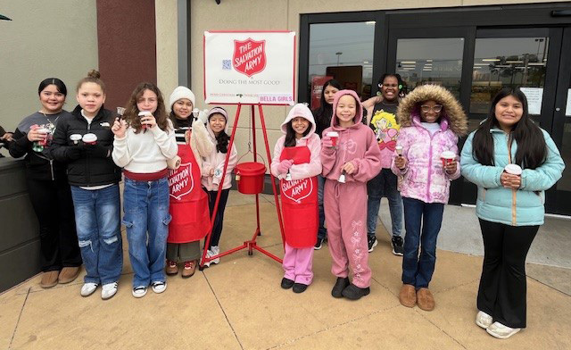 elementary age girls ringing Salvation Army bell outside a store