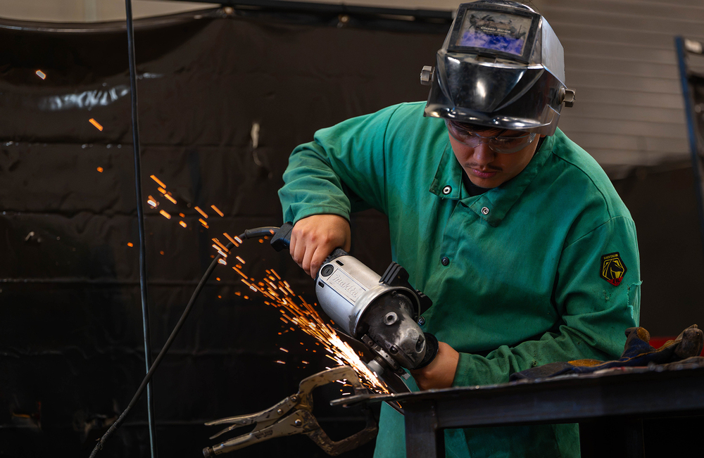 teen boy using grinder on metal with sparks flying