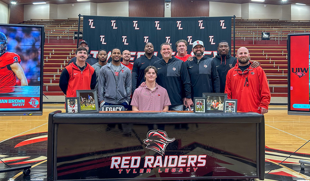 high school boy with his football coaches and players around him in gym