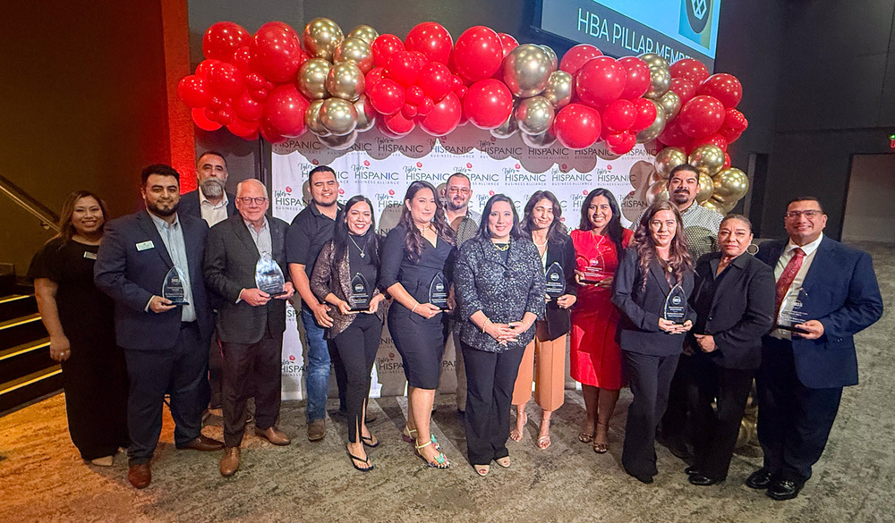 group of adults in front of red and gold balloons