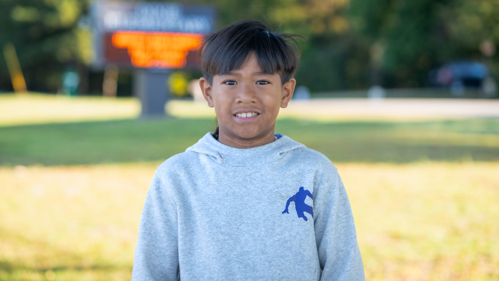 elementary age boy with dark hair wearing a gray sweatshirt