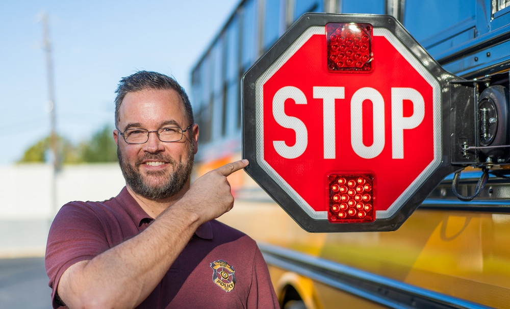 man pointing at stop sign on school bus