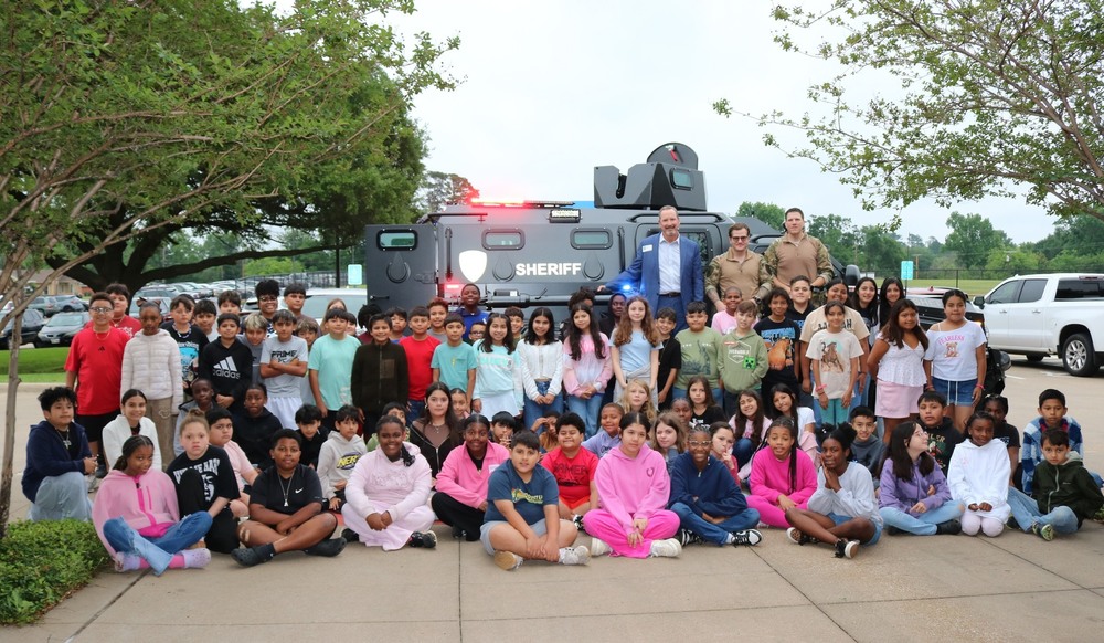 elementary age kids in front of SWAT vehicle in parking lot