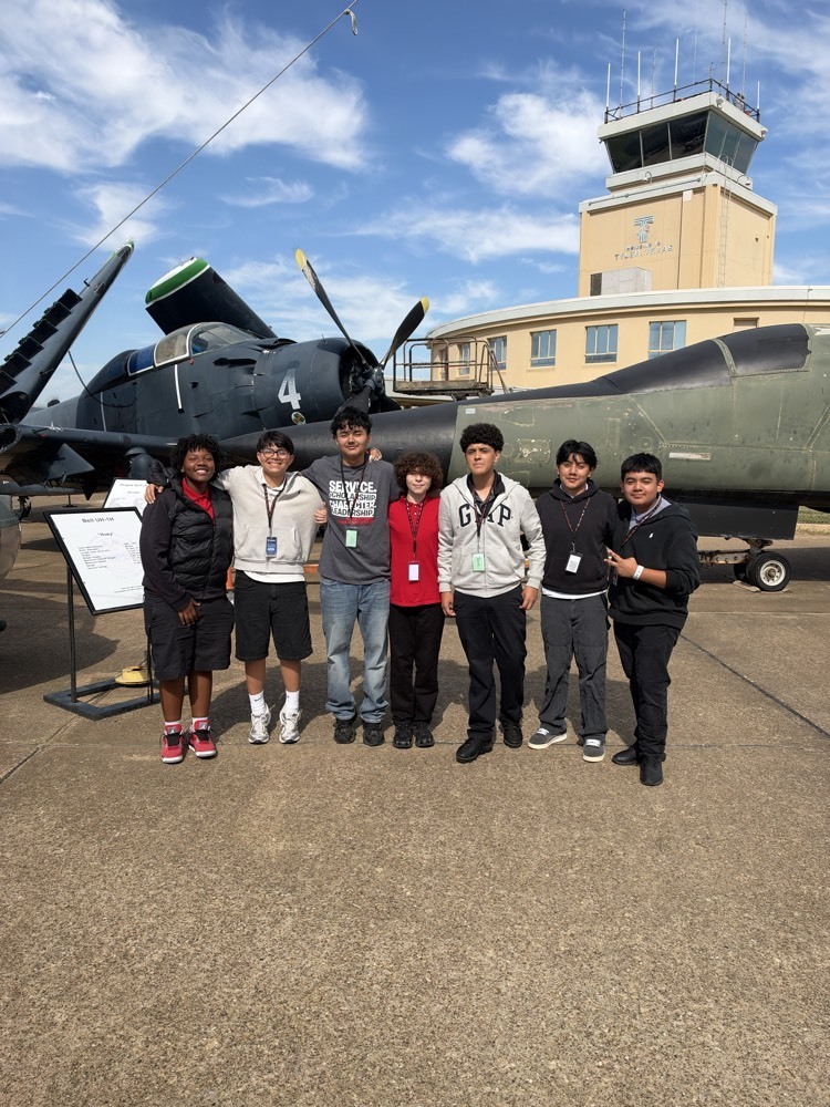 8th grade students standing in front of an airplane
