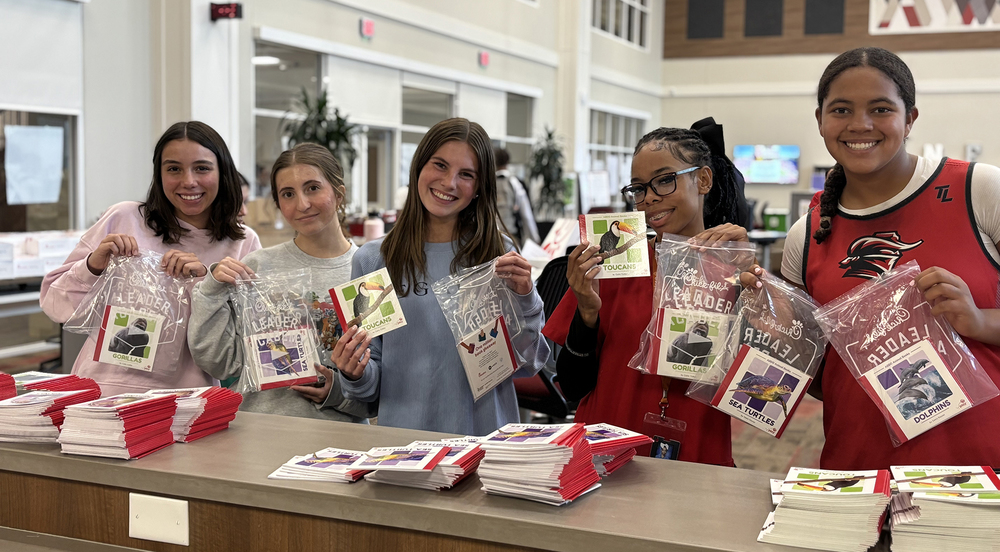 high school girls in a library holding up book packets