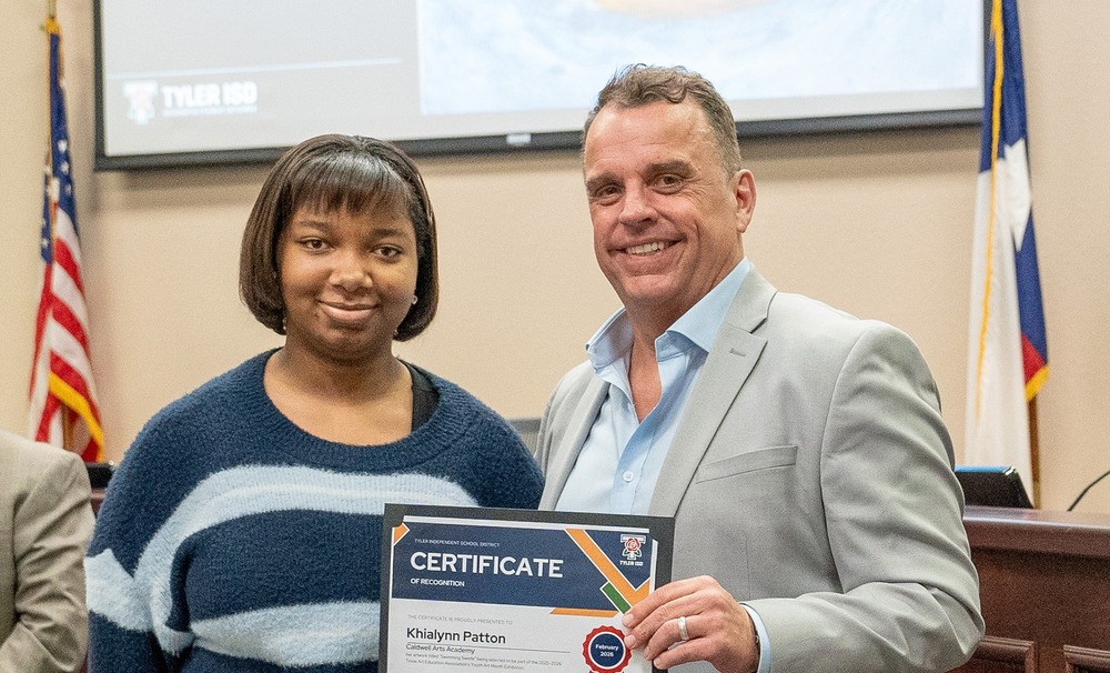 teen girl next to man in suit holding certificate