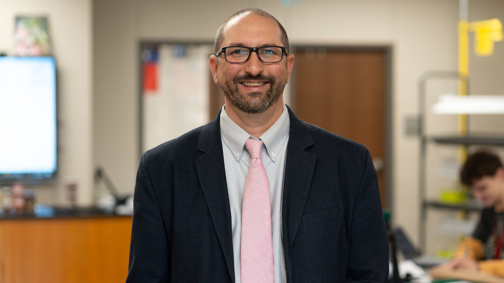 man with beard and glasses wearing a suit jacket with pink tie