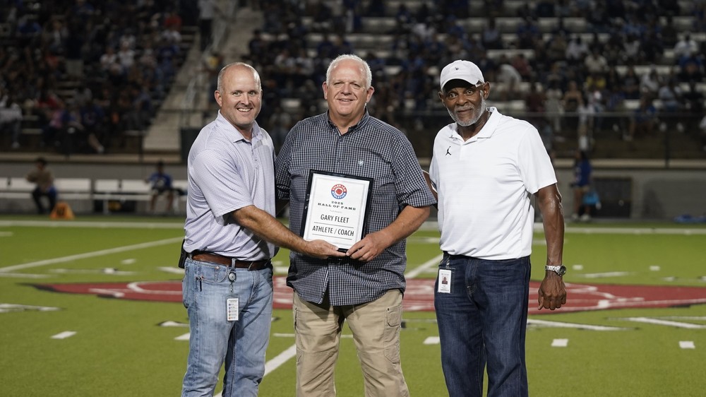 Three men standing on 50 yard line