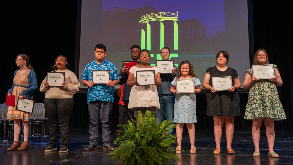 teen boys and girls on stage holding certificates