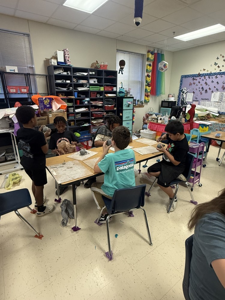 students working at art table on clay whistle project
