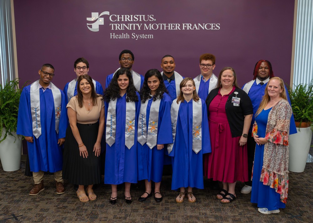 teens in blue graduation gowns standing with three women