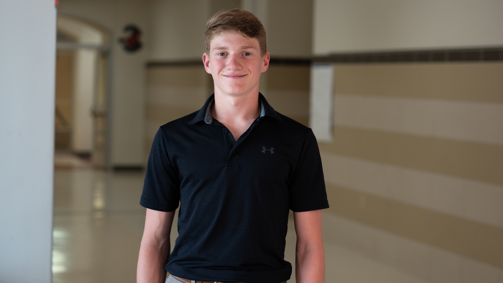teen boy standing in school hallway