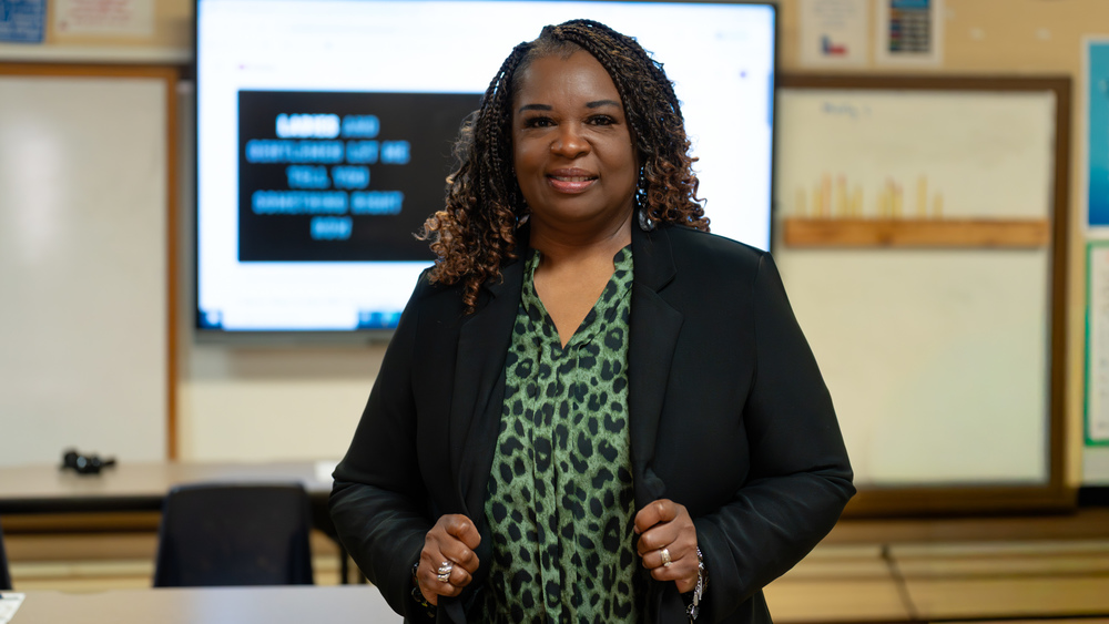 African American woman with black jacket and green blouse in her classroom