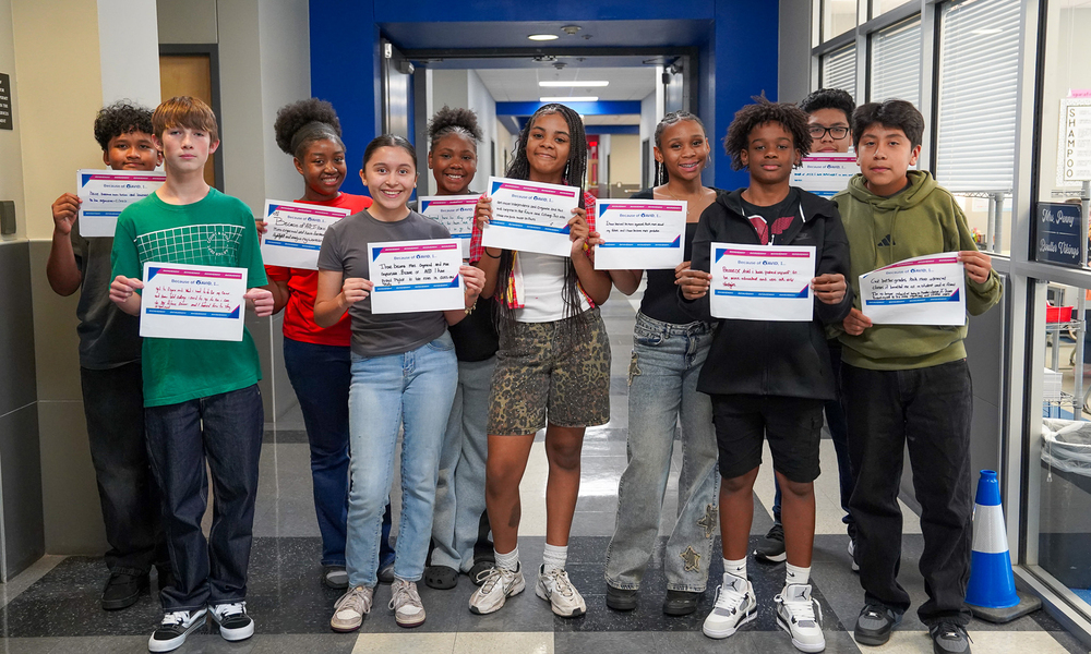 teens standing in hallway at school holding certificates