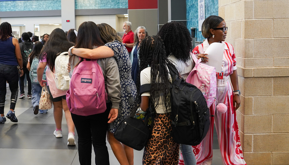 teens and adults walking in school hallway