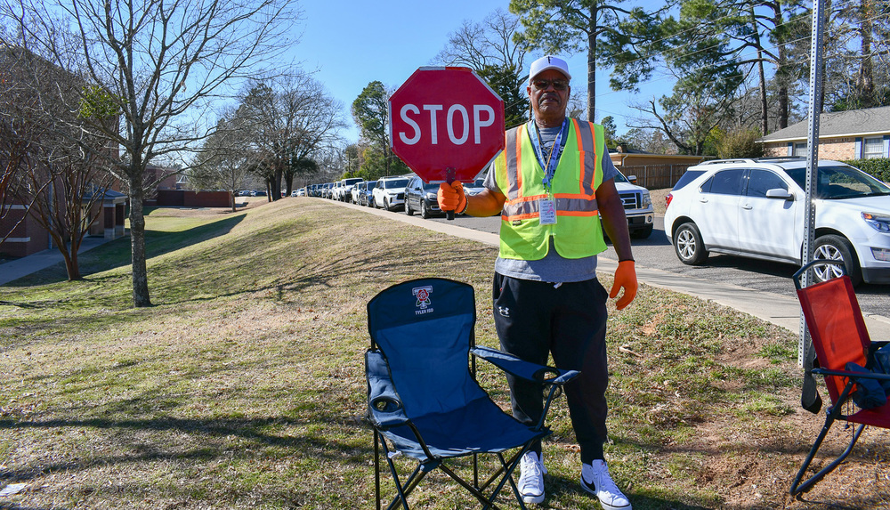 man wearing yellow vest holding stop sign