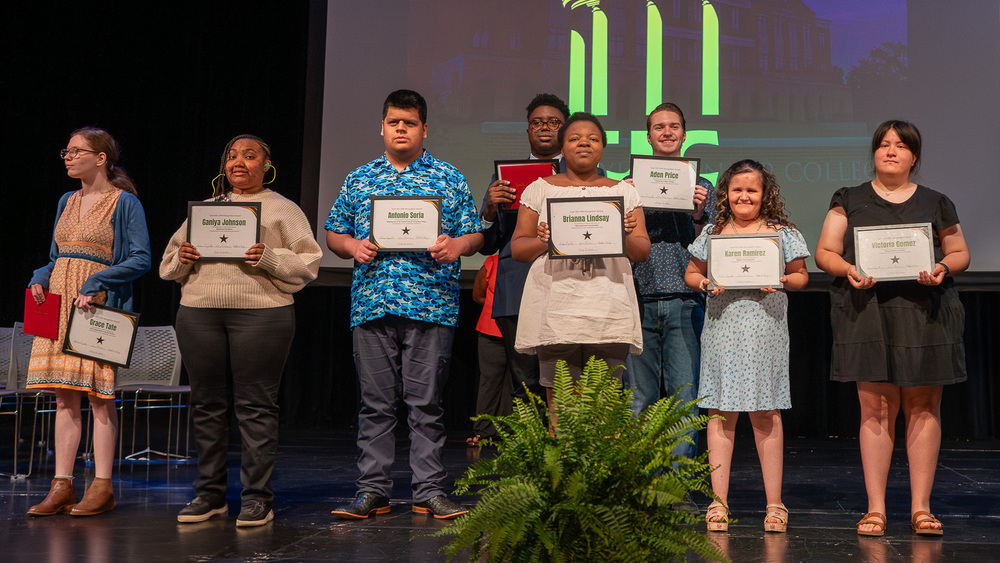 teen boys and girls on stage holding certificates