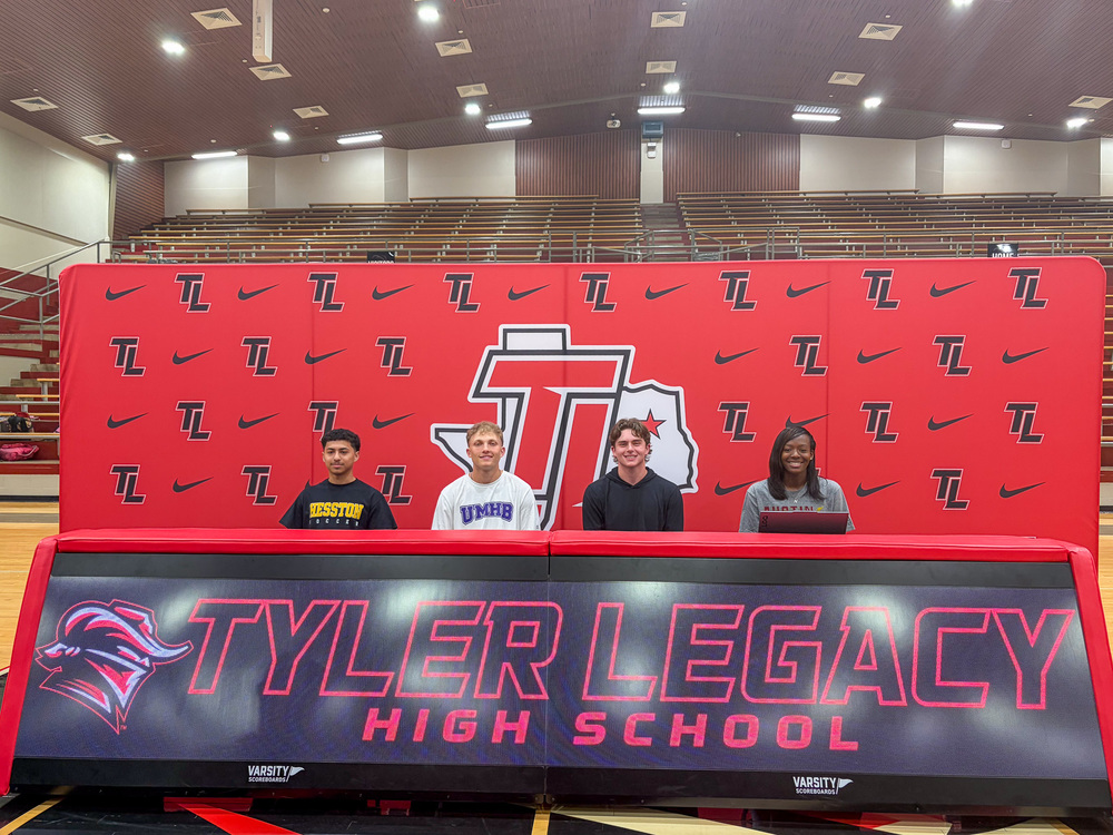 three teen boys and a girl sitting behind table with Tyler Legacy High School sign