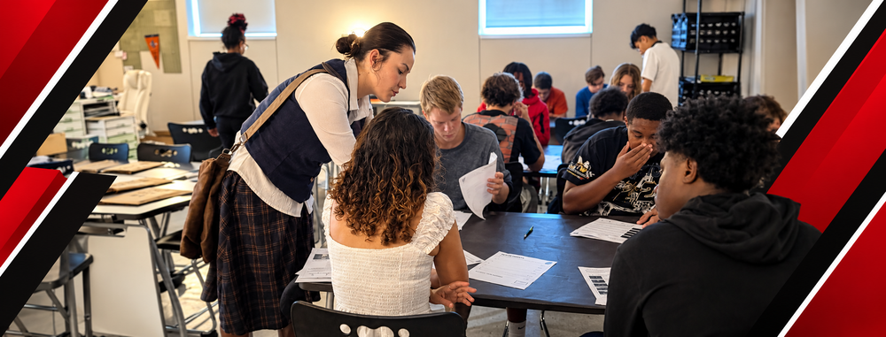 A teacher helps students work together on assignments in a classroom, framed by bold red, black, and white diagonal accents in a Raiders-inspired Facebook cover design.