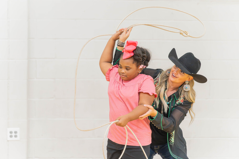 Woman teaches young girl how to swing a lasso
